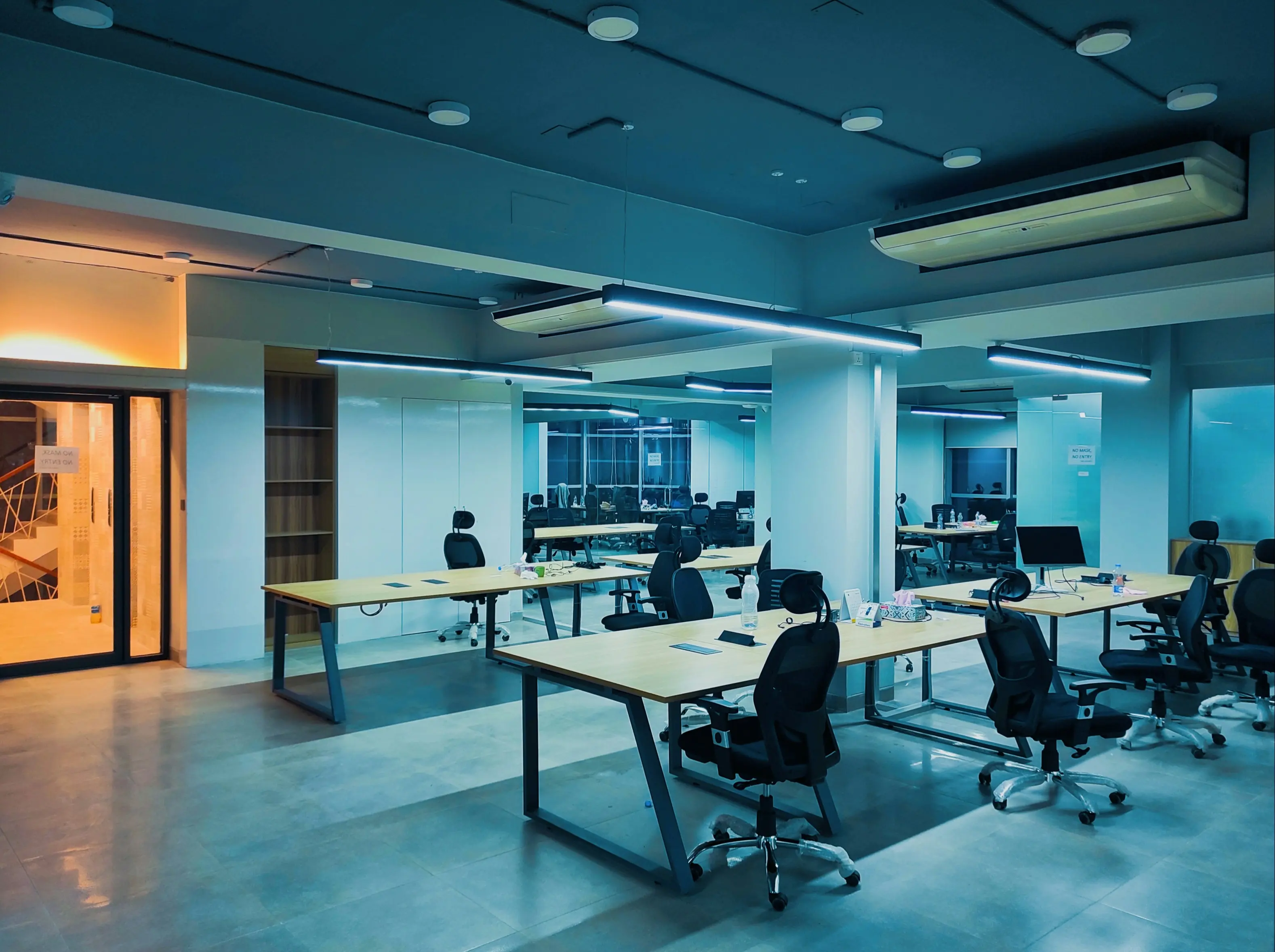 Espace de travail d'un studio web, postes alignés sous un éclairage rasant